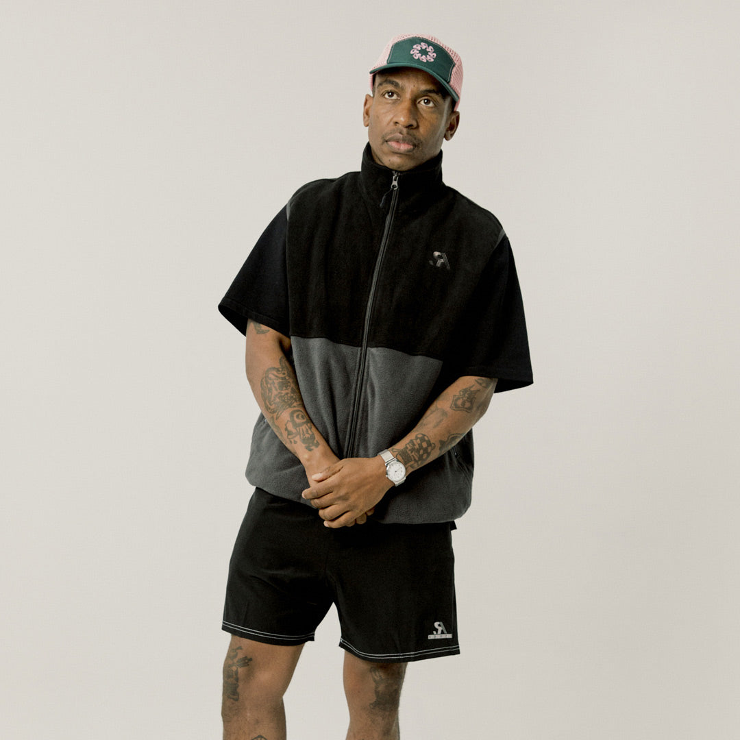 Two-tone black and gray vest with a logo on a white background