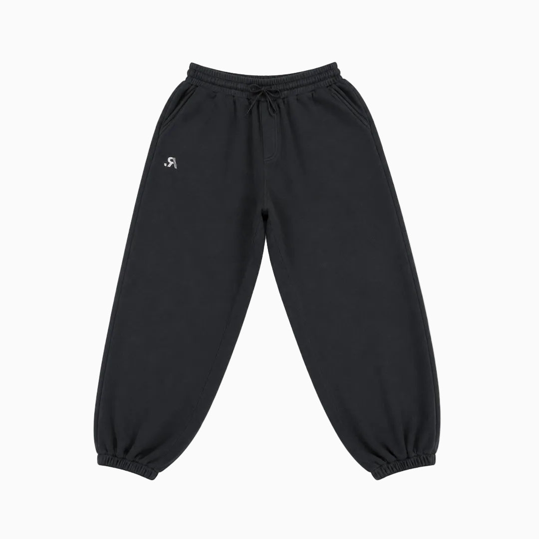Black jogger sweatpants with an elastic drawstring waist and elastic cuffs, featuring a small white stylized logo on the left hip, shown against a plain white background.